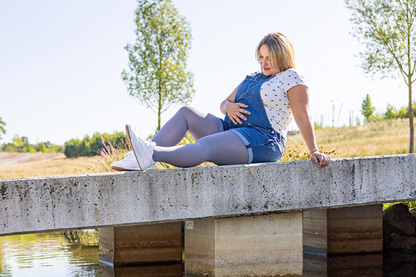 Einne schwangere Frau sitzt auf einer Brücke